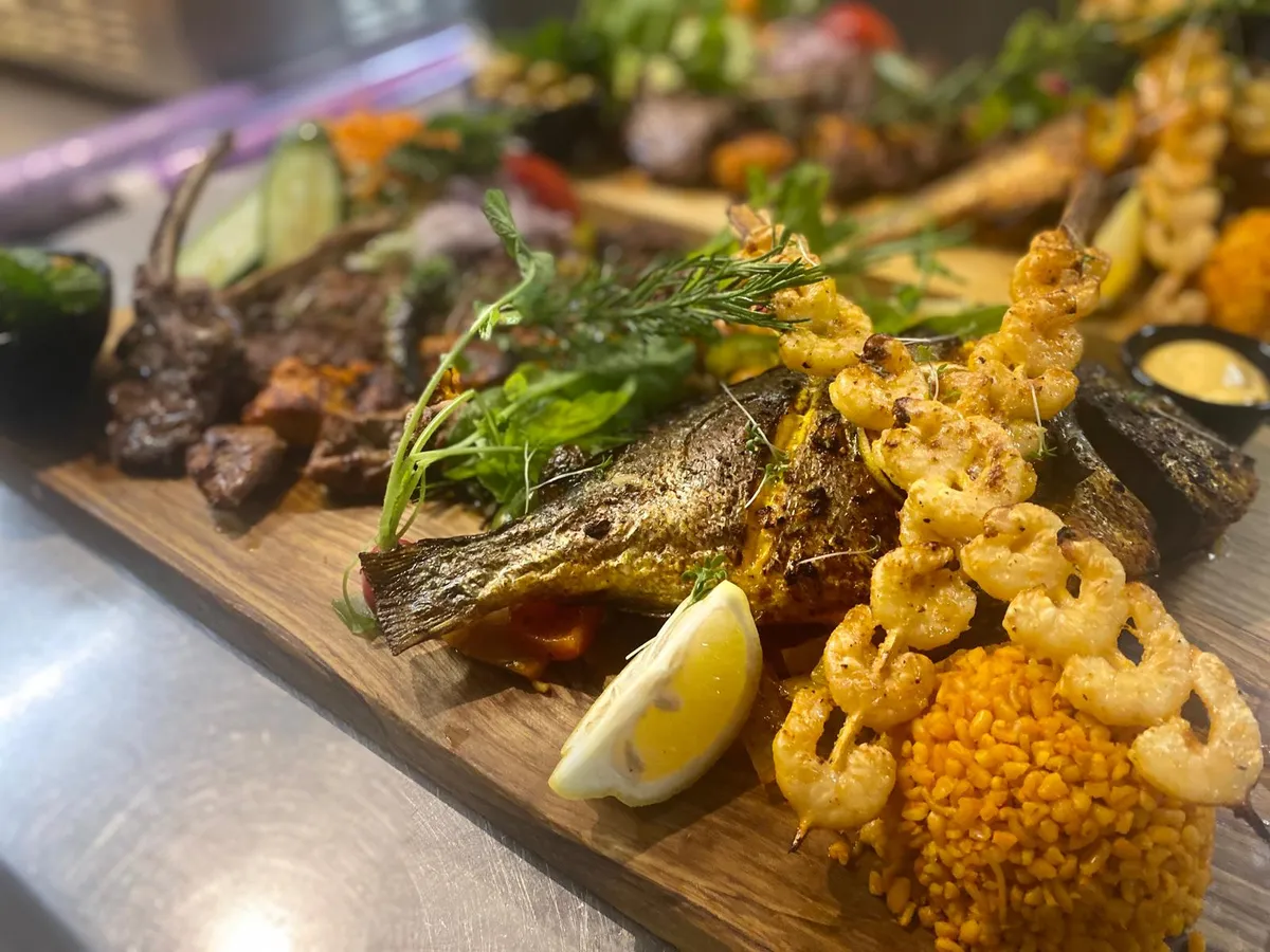 Gegrilde hele vis met gambas en lamsvlees op een houten plank