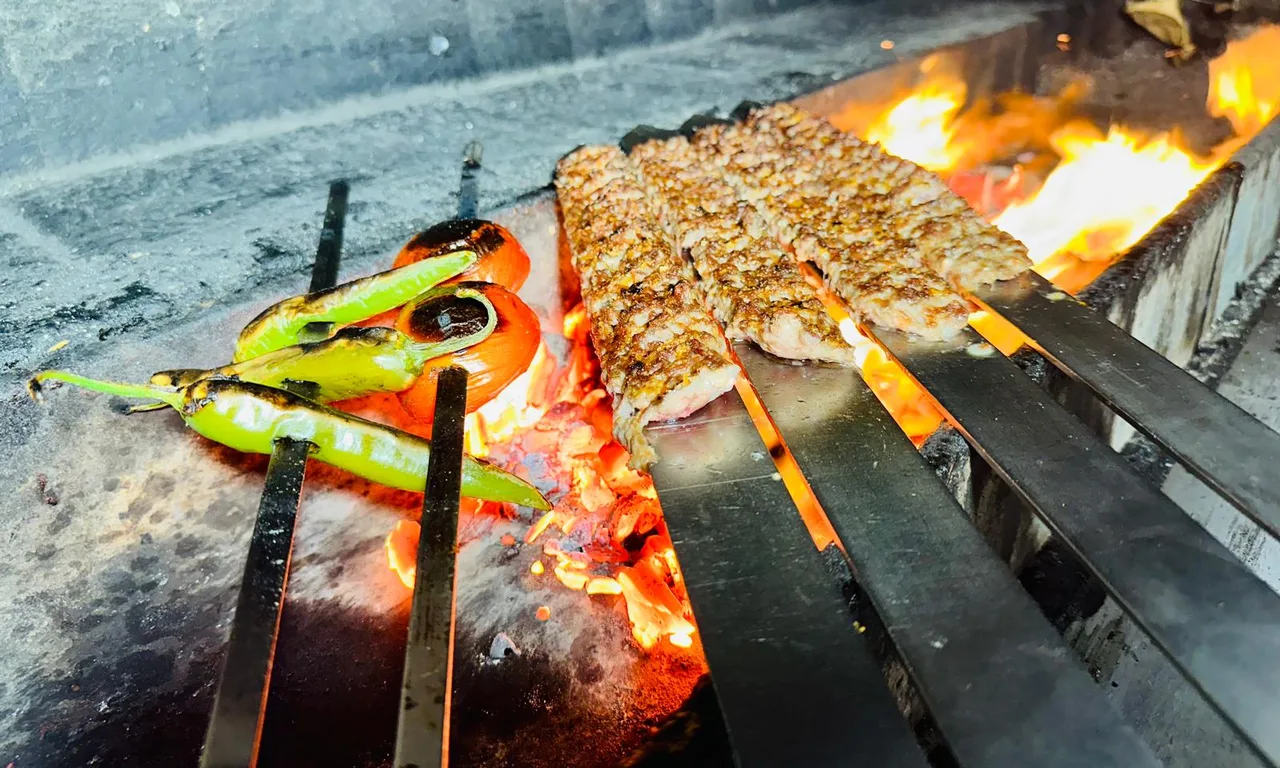 Kebabspiesen en gegrilde groenten boven open vuur op de houtskoolgrill van Al Hayat