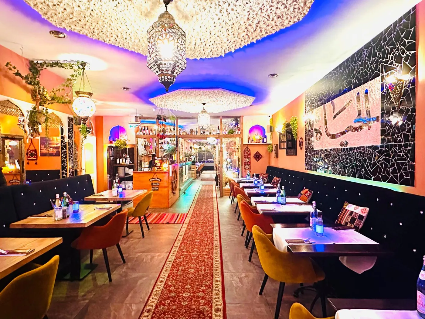 De zaal van Al Hayat: mozaïekplafond, hanglampen, fluwelen banken en de الحياة-wand